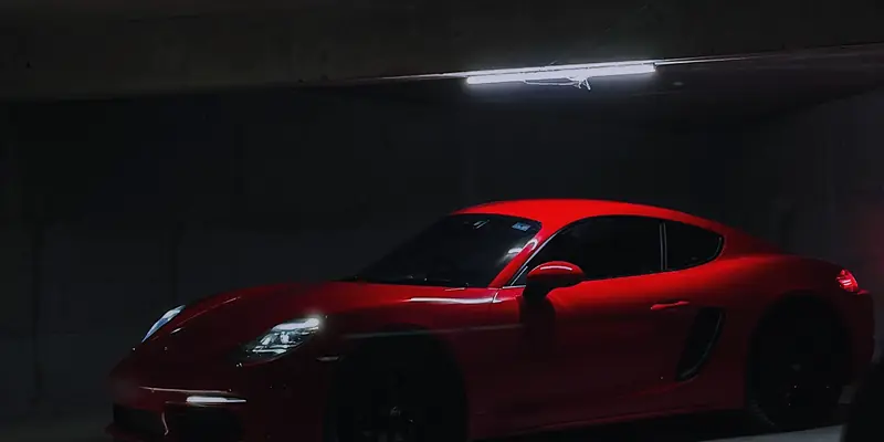 Red Porsche Cayman picked out by a single strip light in the dark