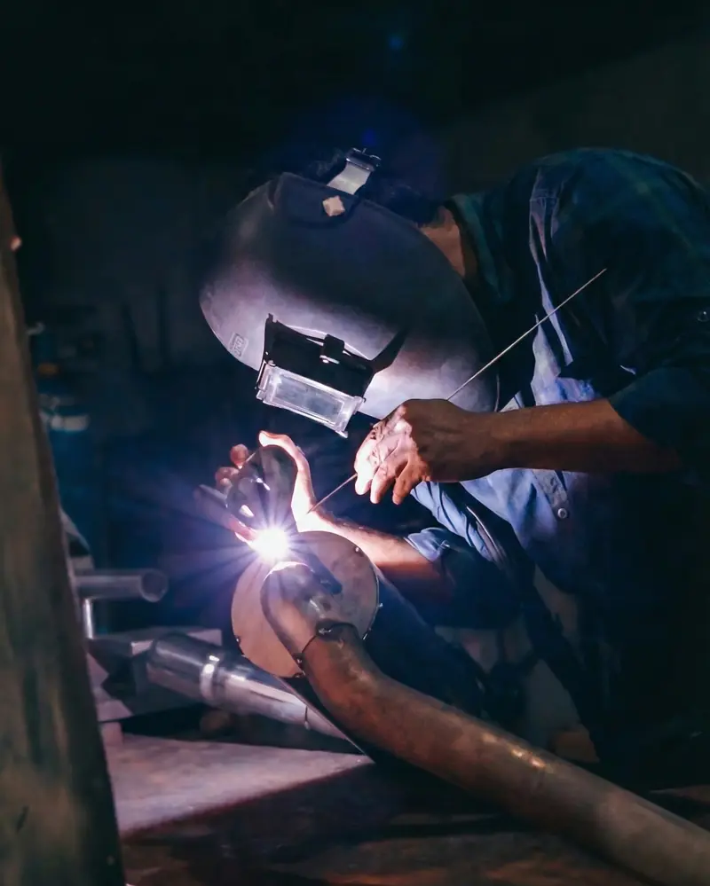Fabricator in a welding mask welding an exhaust section