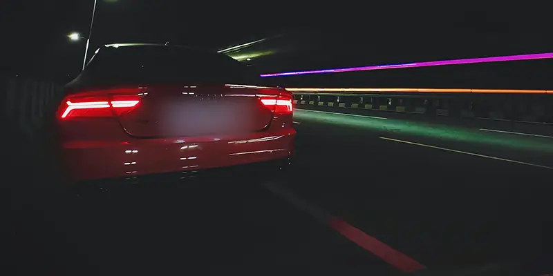 Audi RS7 tail lights on a night highway, light trails streaking past